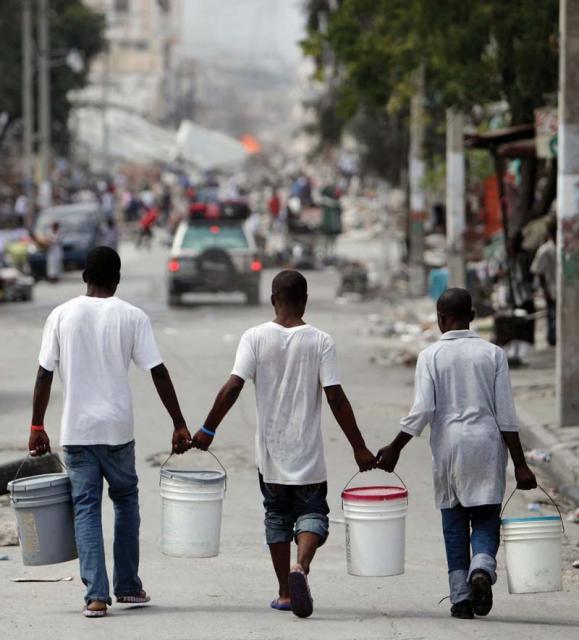 Haiti: Residents pitched in by carrying water in Port-au-Prince last Sunday as relief groups and officials focused on moving the aid flowing into Haiti to survivors of the powerful earthquake that hit the country on Tuesday. (AP Photo/Gregory Bull).